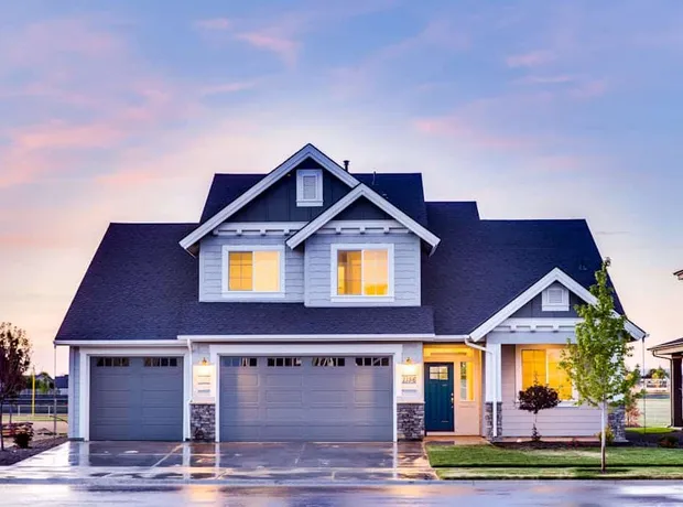 Two-story home at dusk with illuminated windows